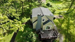 Une maison à deux étages dotée d’une terrasse, entourée d’une végétation luxuriante.