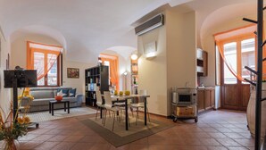 Un salon comprenant un canapé, une table à manger, des chaises et un téléviseur. Il y a également un coin cuisine avec un four à micro-ondes et des placards.