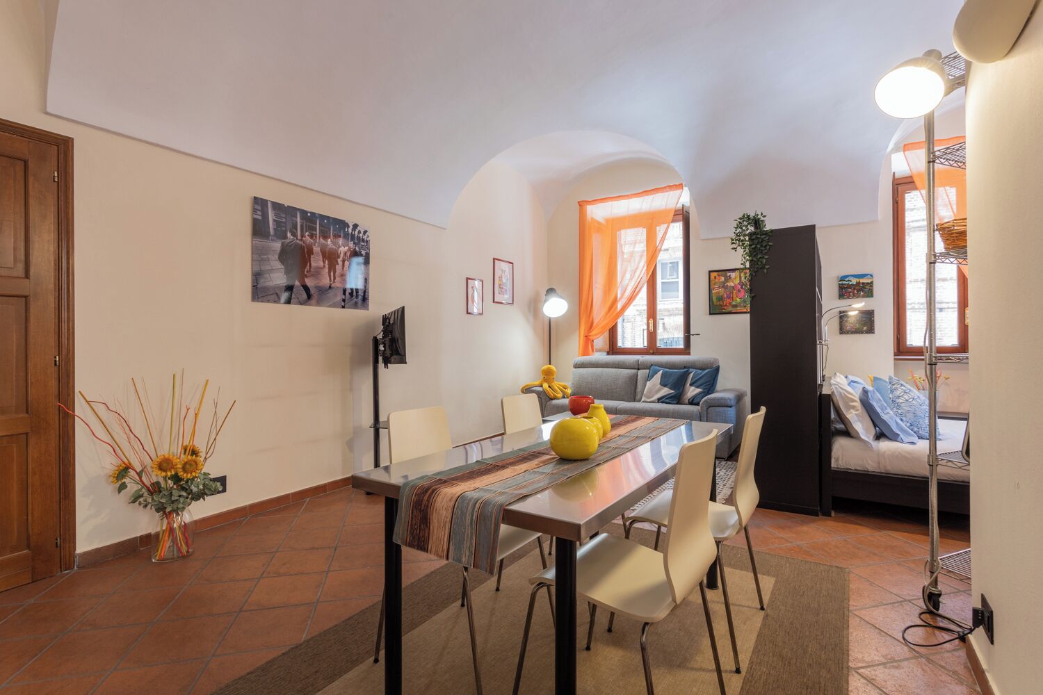 A compact living space with a dining area, a sofa, and a bed.