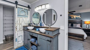 Een badkamer met een rustieke wastafel, twee spiegels en een groot raam.