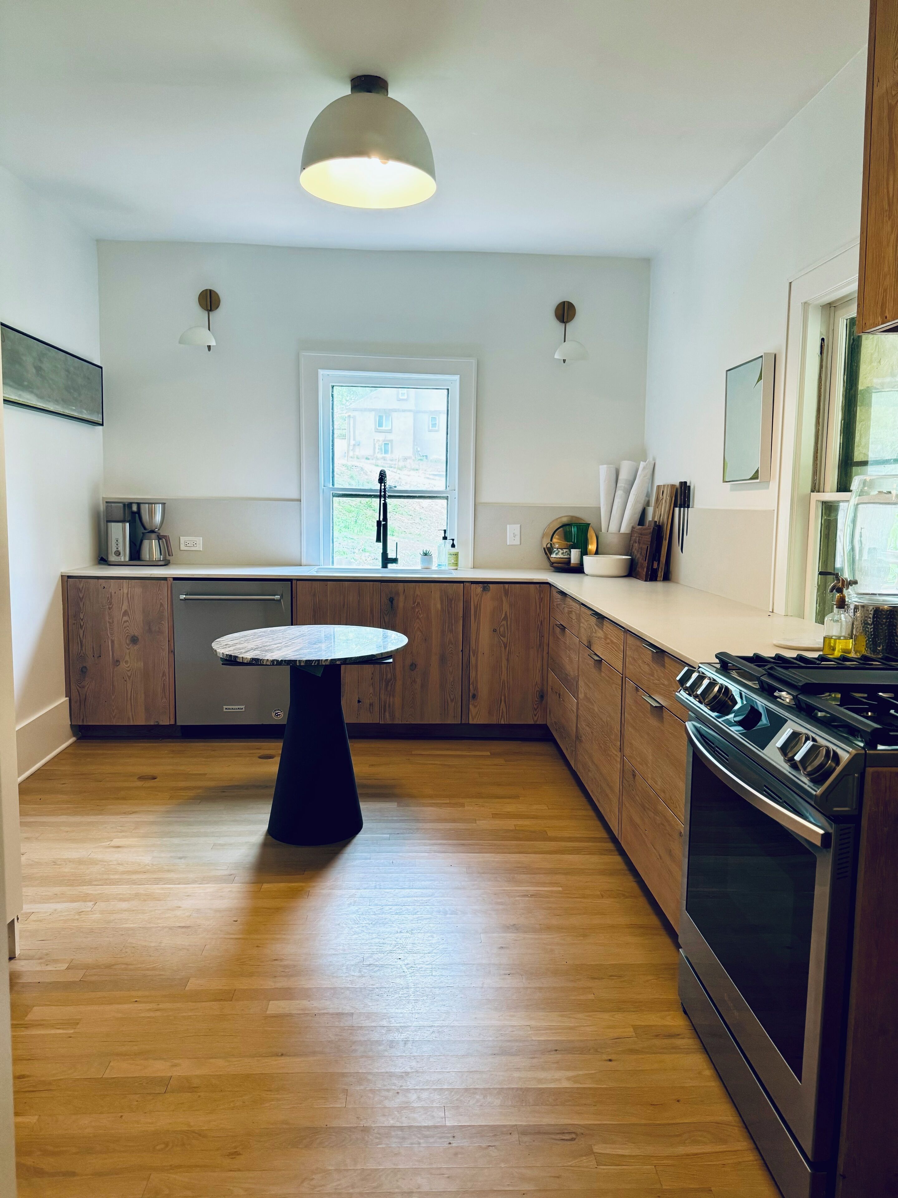 Una cocina moderna con armarios de madera, una isla central, horno empotrado y un ventanal que proporciona luz natural.