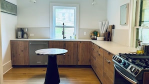 Une cuisine moderne avec des meubles en bois, un îlot central, un four encastré et une fenêtre qui laisse entrer la lumière naturelle.