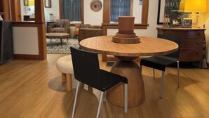 Un espace repas comprenant une table ronde en bois, des chaises noires et un élément décoratif central.