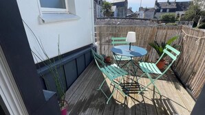 A wooden deck with a table and chairs, a potted plant, and a view of the surrounding buildings. - Charming studio with terrace in the heart of Vannes, 5 minutes from the port (Vannes)