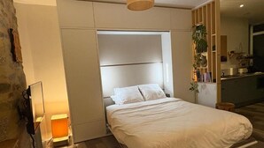 A bedroom with a bed, bedside lamp, and a built-in wardrobe. - Charming studio with terrace in the heart of Vannes, 5 minutes from the port (Vannes)