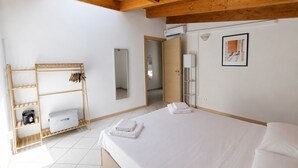 A hotel room with a wooden ceiling, a bed with white linens, a wooden wardrobe, a mirror, and a framed picture on the wall. - BIG Mansard Goldoni [Duomo-M4 Lin Airport] (Milan)