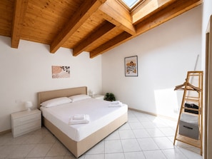 Une chambre à coucher avec un lit, des tables de chevet, une plante suspendue et une échelle en bois.