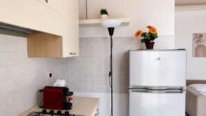 A modern kitchen with a gas stove, a white refrigerator, and a floor lamp. - BIG Mansard Goldoni [Duomo-M4 Lin Airport] (Milan)