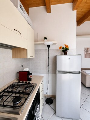 A modern kitchen with a gas stove, a white refrigerator, and a floor lamp.