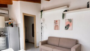 A modern kitchen with a white refrigerator, a dining table with chairs, and a beige sofa in a living area. - BIG Mansard Goldoni [Duomo-M4 Lin Airport] (Milan)