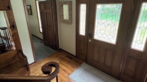 Un escalier en bois menant à une porte dotée d’un panneau de verre, un banc en bois et un tapis à motifs sur un plancher en bois.
