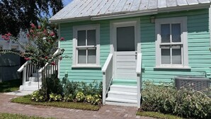 A two-story house with a green exterior, white trim, and a front porch with steps.