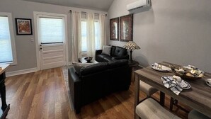 A living room with a black sofa, a dining table with plates, and a ceiling fan.