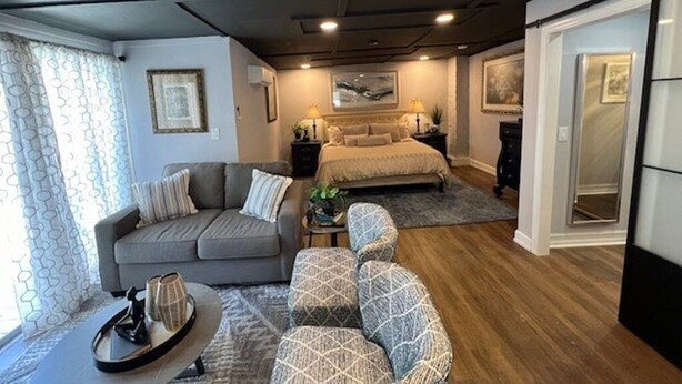 A modern living room with a sofa, armchairs, a coffee table, and a bed with a headboard.