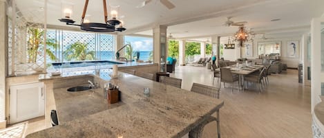 A spacious kitchen with a large island, a dining area, and a view of the ocean.