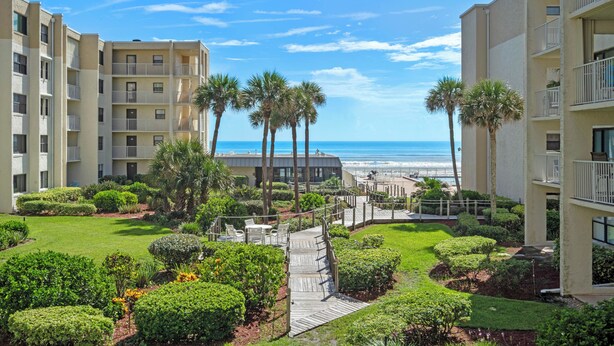 A resort with multiple-story buildings, a well-maintained garden with palm trees, and a view of the ocean. - Castle Reef 213 stunning ocean views (New Smyrna Beach)