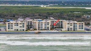 A multi-story hotel with a pool area, located near a body of water. - Castle Reef 213 stunning ocean views (New Smyrna Beach)