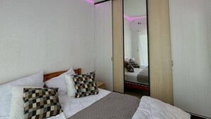 A modern bedroom with a large bed, a mirror, and pink LED lighting along the ceiling. - Pleasant apartment on the ground floor 4DAUP4 (LE BARCARES)