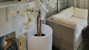 A living room with a white potted tree, a flat-screen TV, a wicker sofa, and a window with curtains. - Pleasant apartment on the ground floor 4DAUP4 (LE BARCARES)