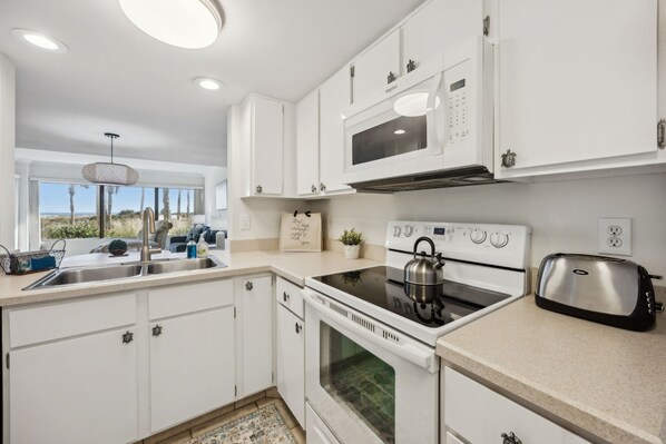 A modern kitchen with white cabinets, a stainless steel toaster, a kettle, and a microwave.