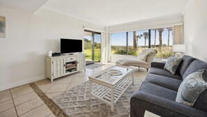 Un salón con televisor, sofá y vistas al exterior.