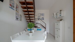 Un coin repas avec une table blanche, des plantes en pot et un escalier doté de rampes en bois.