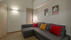 A modern living room with a grey sectional sofa, wooden flooring, and two wall-mounted artworks.