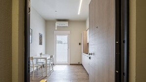 A hallway with a wooden floor, a white door, and a dining area with a table and chairs.
