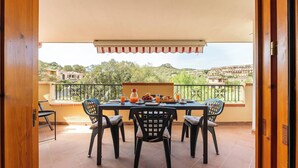 A balcony with a table set for breakfast, chairs, and a view of a hillside. - Relax Sea Home by Propertize - Villasimius (Villasimius)