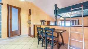 Un comedor con una mesa y sillas de madera, una escalera y una puerta con panel de vidrio.