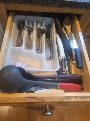 A drawer with utensils and a grater.