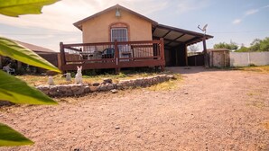 A single-story house with a porch, a satellite dish, and a stone wall.
