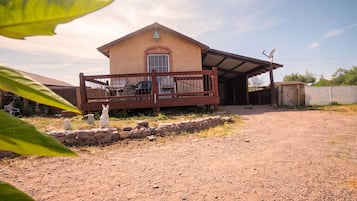 A single-story house with a porch, a satellite dish, and a stone wall.