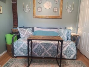 Un coin salon confortable avec un canapé, une petite table et des œuvres d’art décoratives accrochées au mur.