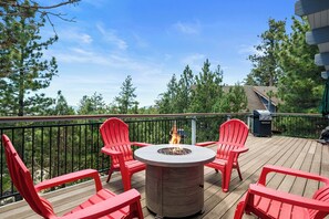 Eine Holzterrasse mit einem runden Tisch und vier roten Stühlen, umgeben von einem schwarzen Metallgeländer.