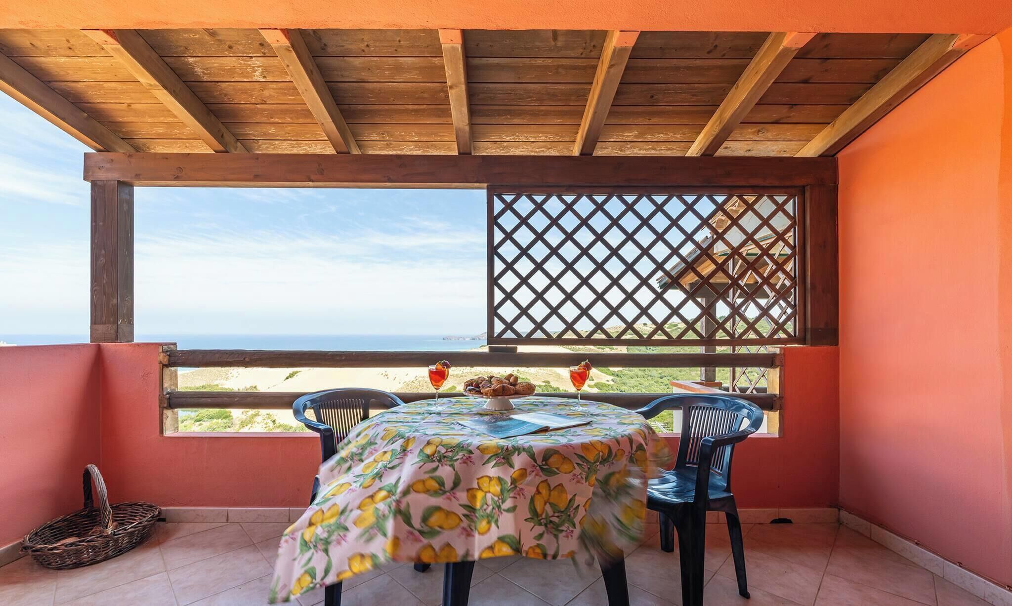 Un patio techado con una mesa preparada para dos, con vista a la playa.