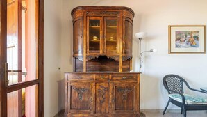 Eine Holzschrank mit Glastüren und ein Korbstuhl.