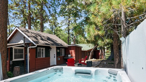 Ein Garten mit Whirlpool, einem kleinen Haus und einem roten Stuhl.