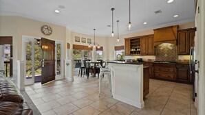 A spacious kitchen with a central island, wooden cabinets, and pendant lighting.