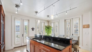 A spacious kitchen with a large island, white cabinetry, and a black countertop.