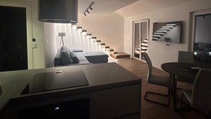 Una sala de estar moderna con una escalera, un televisor de pantalla plana y un comedor.