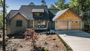 A two-story house with a garage, a covered porch, and a landscaped front yard. - Spacious & Modern Rumbling Bald Retreat! Hot Tub, Fire Pit, Game Room (Lake Lure)
