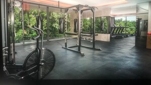 A gym with various exercise equipment, large windows, and a view of greenery. - Penthouse de Lujo con 3 Recamaras, Baños, Sala Comedor, Cocina, Jacuzzi Privado (Tulum)