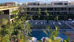 A modern hotel with a rooftop pool, multiple floors, and lush greenery. - Penthouse de Lujo con 3 Recamaras, Baños, Sala Comedor, Cocina, Jacuzzi Privado (Tulum)