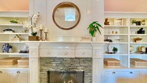 A living room with a fireplace, shelves with decorative items, and a mirror above the fireplace. - New Charming Spacious Disneyland Pool Home (Santa Ana)