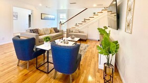 A spacious living room with a staircase, two sofas, a coffee table, and a potted plant. - New Charming Spacious Disneyland Pool Home (Santa Ana)