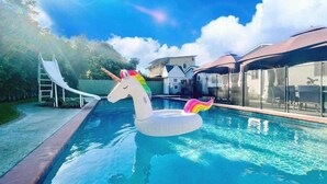A swimming pool with a unicorn float and a slide. - New Charming Spacious Disneyland Pool Home (Santa Ana)