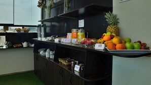 A breakfast buffet with various fruits, beverages, and a sign indicating self-service. - Hotel TerraMistica Monasterio  (Arequipa)