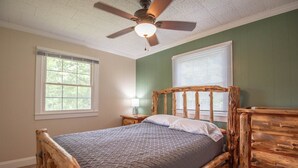 A bedroom with a wooden bed frame, a ceiling fan, and a window with blinds.