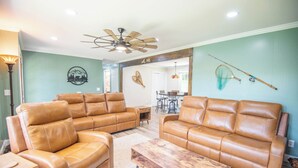 A living room with two brown leather sofas, a wooden coffee table, and a ceiling fan.